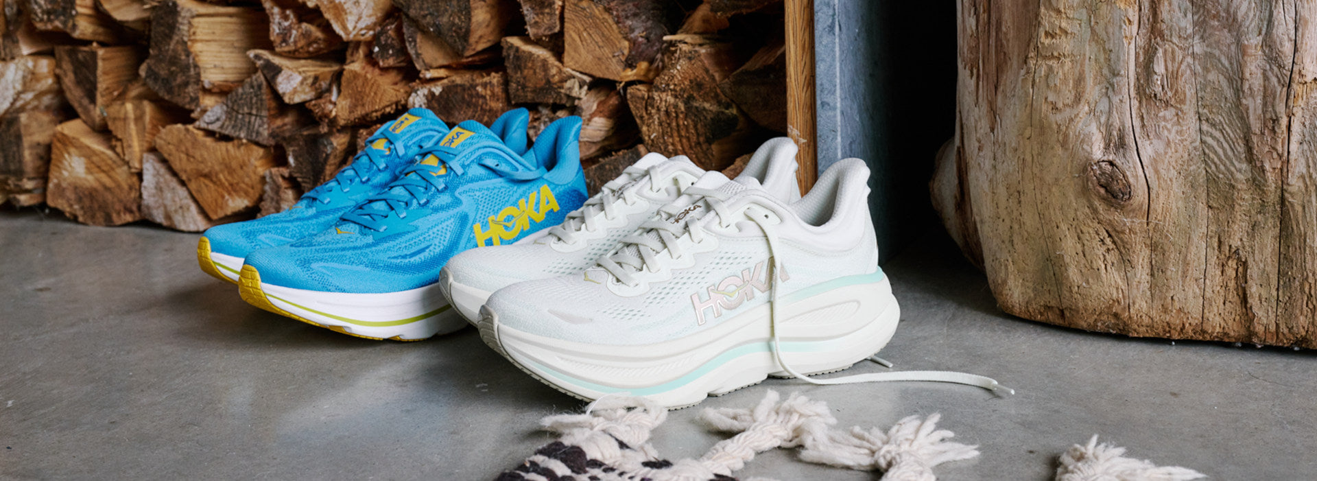 Blue and white Hoka Clifton 10 shoes next to a wood pile